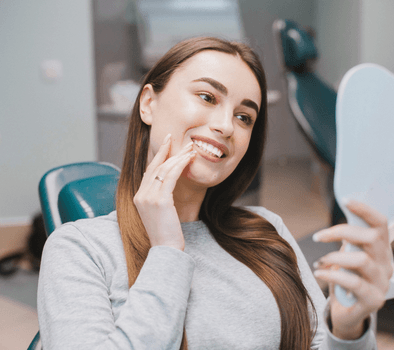 woman looking at a mirror sitting in a dental clinic