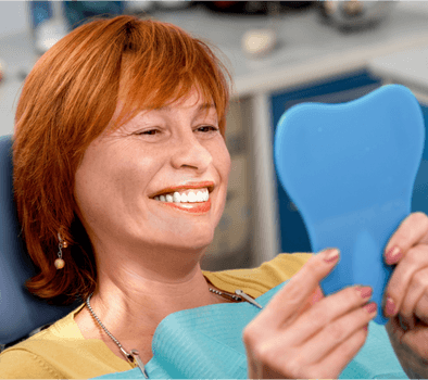 woman sitting in a dental clinic looking at a mirror