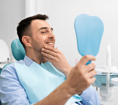 man looking at a mirror sitting in a dental clinic